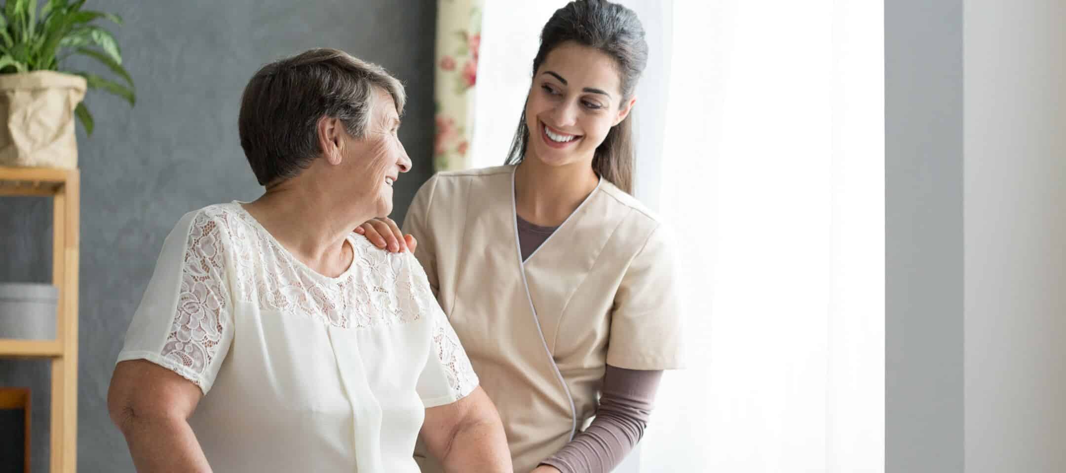 Photo d'une jeune femme aidant une femme âgée, toutes les deux souriantes