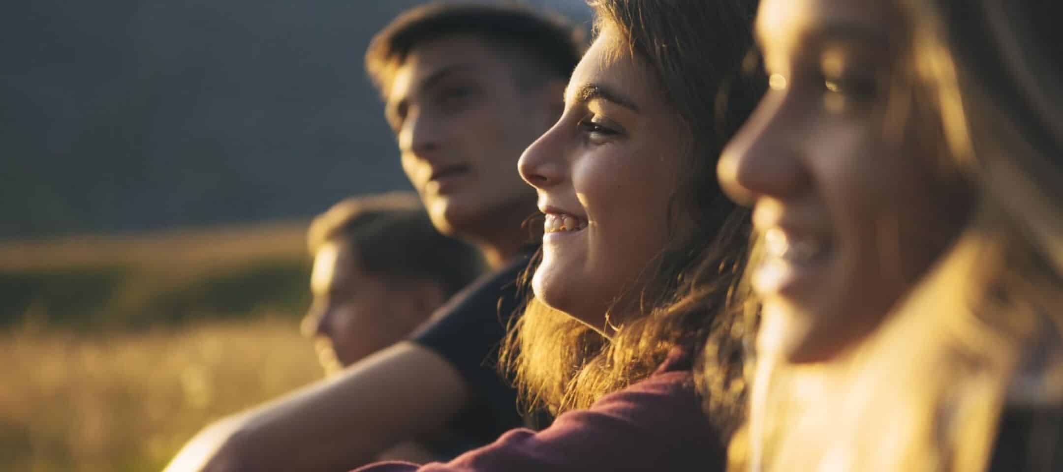 Photo de jeunes adultes souriants assis dans un champs