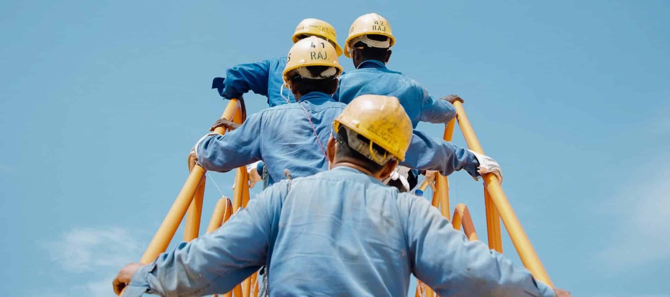 Photo d'homme montant un échafaudage avec des casque chantier